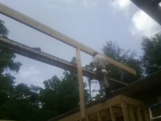 Carpenter setting a ridge beam over a new addition frame — Ice Dam Removal by Roofing Brothers in Austin